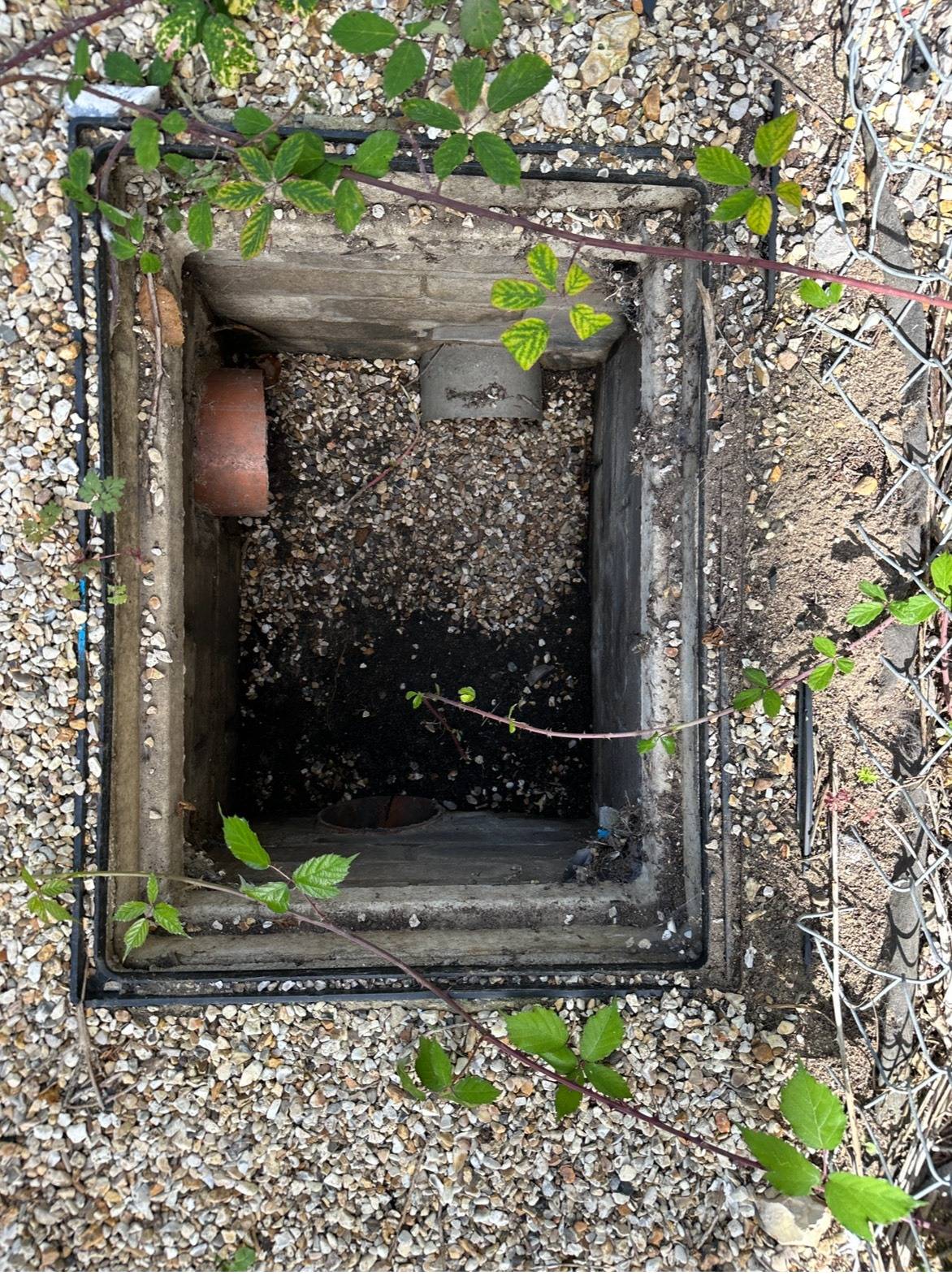 Open manhole cover showing drain pipes during inspection
